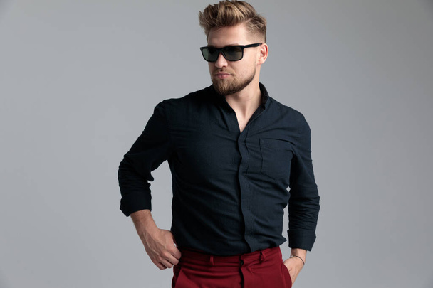 Przekonany mężczyzna moda regulować spodnie i odwracając wzrok - Zdjęcie, obraz