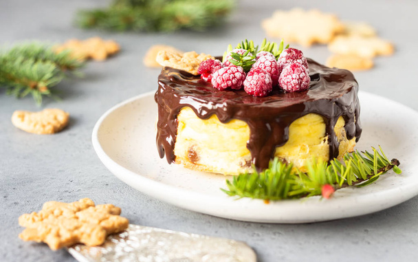 Delicious New York cheesecake with chocolate ganache, raspberries and cookies with fir branches. Festive decoration.  - Fotoğraf, Görsel