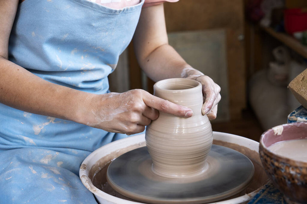 Girl Potter sculpts a pitcher of clay on a Potters wheel. - Фото, изображение