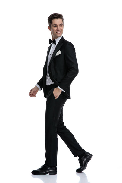 side view of young elegant groom in tuxedo walking - Photo, Image