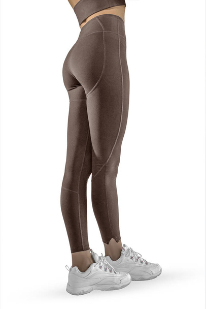 Belle gambe femminili sottili in leggings sportivi marroni e scarpe da corsa isolate su sfondo bianco. Concetto di vestiti alla moda, sport, bellezza, moda e gambe sottili
 - Foto, immagini