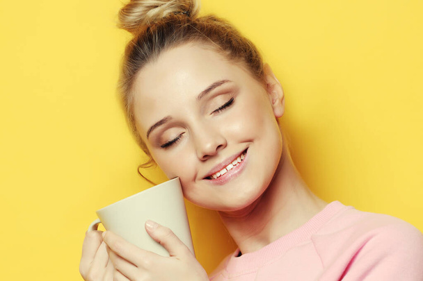 lifestyle, food and people concept: young pretty woman drinking coffee over yellow background - Фото, зображення