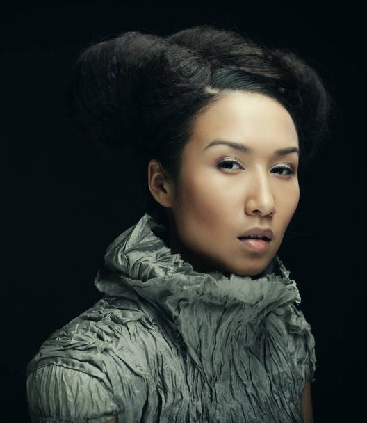 Beauty and fashion concept: young Asian fashion model in grey dress against black background - Φωτογραφία, εικόνα