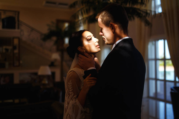 Young married couple in darkness. Newlyweds enjoy each other tenderly. Intimate atmosphere. Luxury elegant wedding couple kissing and embracing. Romantic moment. Together. Wedding. - Foto, afbeelding