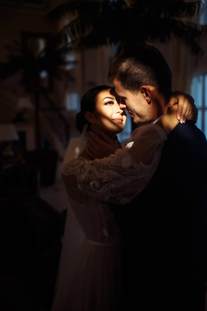 Young married couple in darkness. Newlyweds enjoy each other tenderly. Intimate atmosphere. Luxury elegant wedding couple kissing and embracing. Romantic moment. Together. Wedding. - Foto, afbeelding