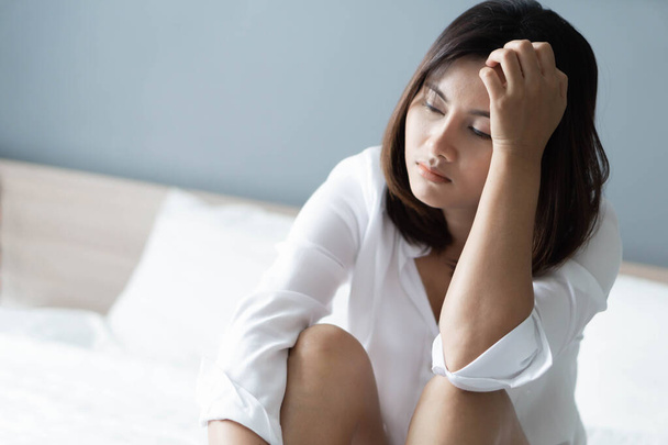 Closeup γυναίκα κάθεται στο κρεβάτι στο υπνοδωμάτιο με τη σκέψη ή κατάθλιψη συναίσθημα, επιλεκτική εστίαση - Φωτογραφία, εικόνα