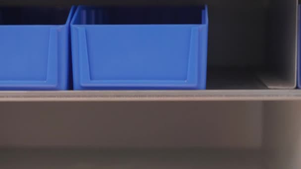 Üres polcok és dobozok automatizált függőleges körhinta tárolására termelés raktárban, néhány lövés. Kék és fehér tartályok automatikus polcon mozgó alkatrészek számára. Automatizálási technológia a gyártás során történő elrendezéshez - Felvétel, videó