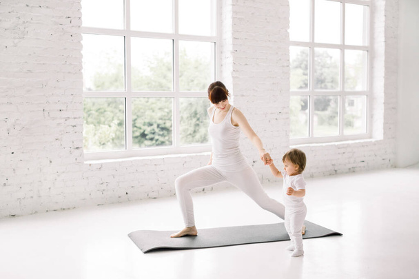 young mother does physical fitness exercises, lunges together with her little baby - Zdjęcie, obraz