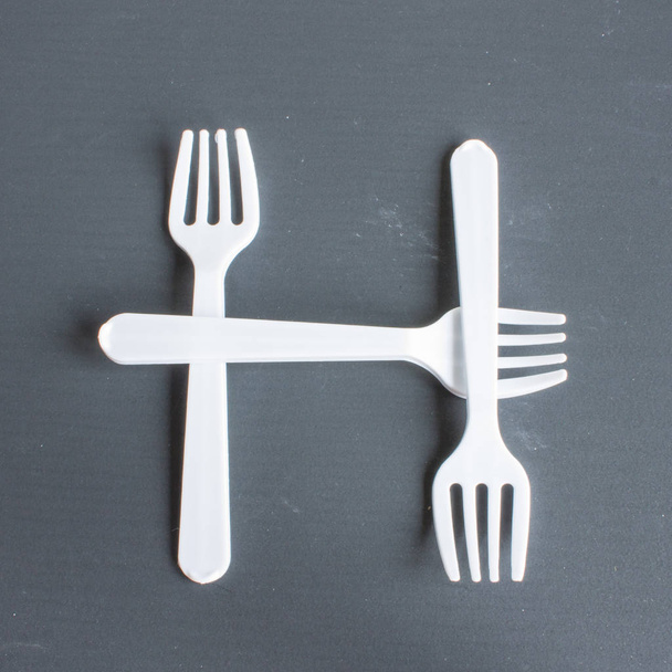 The letter h of white plastic forks on a gray background - Foto, immagini
