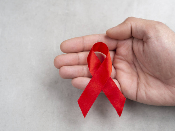 AIDS day ribbon in hand isolated on wall background. 1st December day concept - Photo, Image