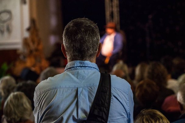 Un homme portant un sac à dos à bandoulière écoute une conférence publique
 - Photo, image