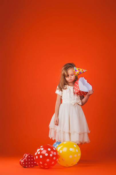 Turuncu arka planda hediyeleri ve balonları olan bir kız.. - Fotoğraf, Görsel