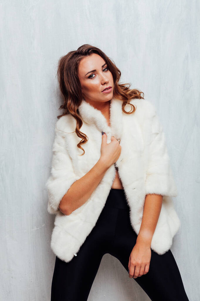portrait of a beautiful fashionable woman with curls in a white fur coat - Photo, Image