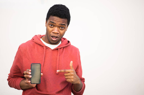 Πορτρέτο του Αφροαμερικανού άνδρα που κρατά το κινητό τηλέφωνο και δείχνει προς την οθόνη - Φωτογραφία, εικόνα