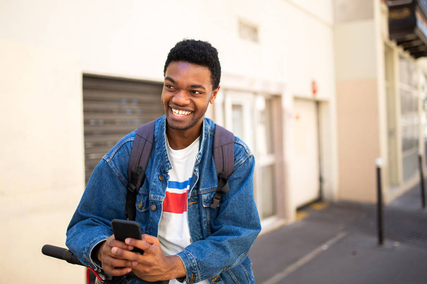 Πορτρέτο του δροσερό αφροαμερικανός νεαρός άνδρας με κινητό τηλέφωνο στην πόλη - Φωτογραφία, εικόνα