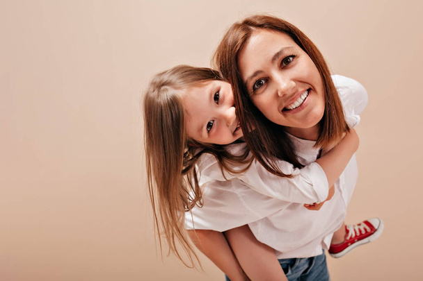 Primo piano ritratto di donna felice sorridente con figlia che indossa camicie bianche divertirsi e godersi il tempo libero
 - Foto, immagini