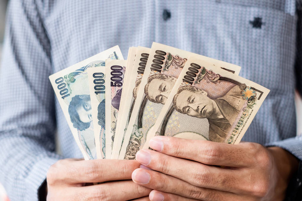 Liikemies kädessään Japanin jeni setelipino. liiketoiminta
,  - Valokuva, kuva