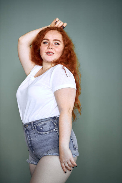 Funny smiling plus size young redhaired girl posing studio - Foto, imagen