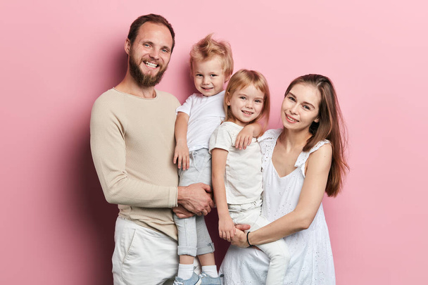 Onnellinen nuori perhe, jolla on suloinen pieni tytär poseeraa vaaleanpunaisella taustalla
 - Valokuva, kuva