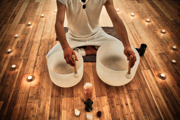 Young Man playing crystal bowls as part of a meditative concert - Fotó, kép