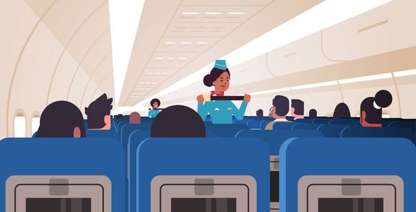 緊急時のシートベルト締結の使い方を乗客に説明するスチュワーデスアフリカ系アメリカ人乗務員統一安全デモコンセプト機内水平 - ベクター画像