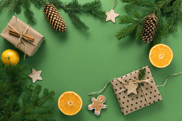 Christmas composition. Gifts, branches of spruce, pine cone and oranges, on a green background. Christmas, winter, new year concept. Flat lounger, top view, copy space - Valokuva, kuva