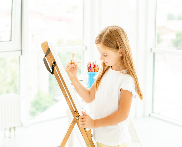 Kid girl painting different pictures on easel - Photo, Image