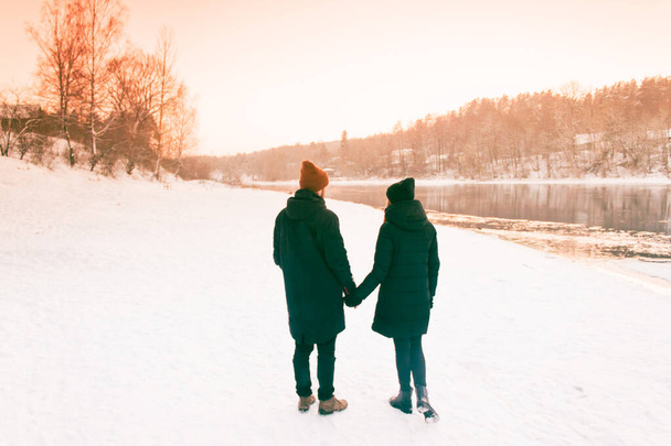 離れて歩いて手を繋いでいるカップル。冬、日当たりの良い、フォレスト、レクリエーション、レジャー、衣料品. - 写真・画像