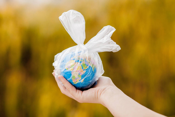 The human hand holds the planet earth in a plastic bag. The concept of pollution by plastic debris. Global warming due to greenhouse effect. - Foto, imagen