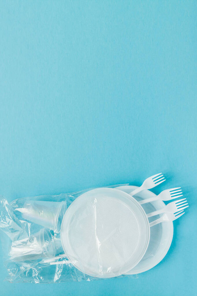 Plastic dishes on a blue background. Disposable tableware - Foto, afbeelding