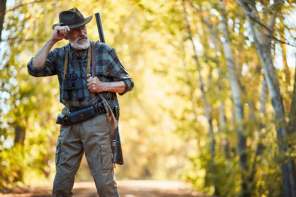 Mature hunter wearing cowboy hat looking away in forest - Foto, Imagem