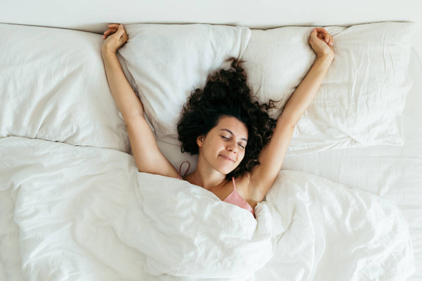 Молодая красивая женщина в постели с белыми простынями яркий свет
 - Фото, изображение