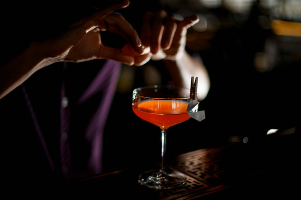 Male bartender spraying on the cocktail decorated with paper airplane in the clothespin with a orange zest juice - Zdjęcie, obraz