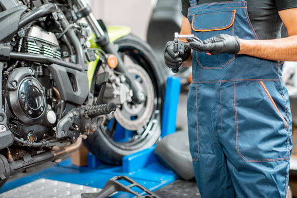 Mechanic repairing motorcycle at the workshop - Foto, immagini