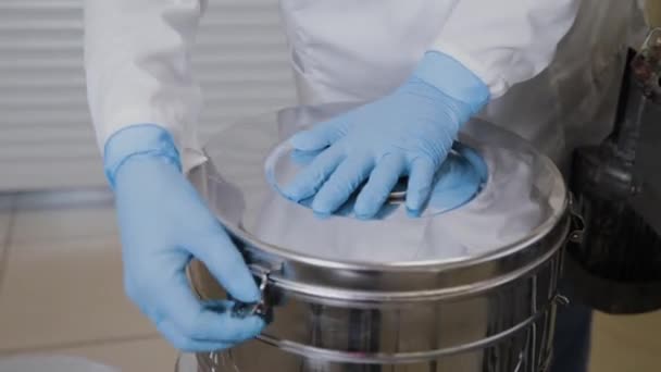 Laboratoriummedewerker stopt medicijnflesjes in sterilisatie container. - Video