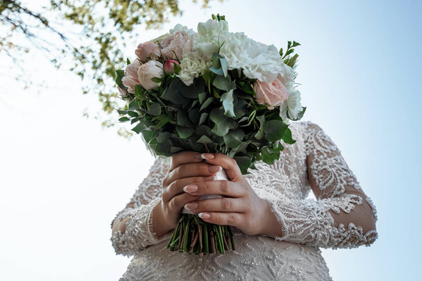 Hochzeitsserie 25. Hochzeitsstrauß aus bunten Rosen in der Hand der Braut. - Foto, Bild