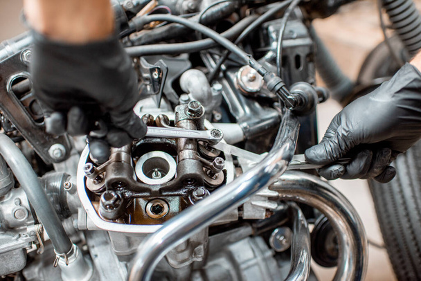 Trabajador reparando motor de motocicleta en el taller
 - Foto, Imagen