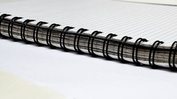 Черное переплетение толстой тетради на белом столе
 - Фото, изображение