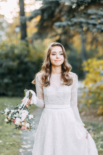 Autumn wedding in European style. Beautiful bride in white dress in the Park.  - Photo, image