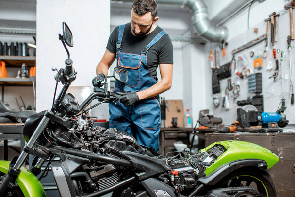 Mechanic repairing or tuning motorcycle - Фото, изображение