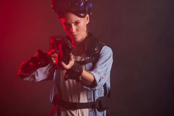 serious woman gamer holding gun isolated in neon backlit - Φωτογραφία, εικόνα