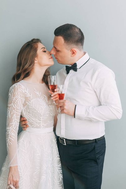 Stylish wedding in European style. Beautiful couple celebrating and drinking champagne in the Studio.  - Fotografie, Obrázek