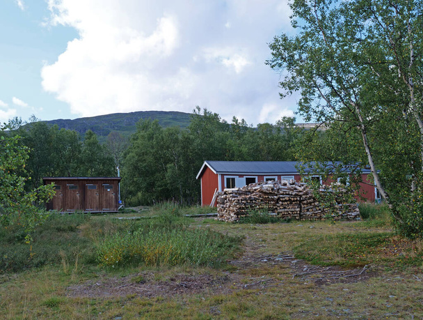 red building of AbiskoJaure STF mountain hut. Green hills, birch forest on the Kungsleden Trail, summer blue sky - Photo, Image