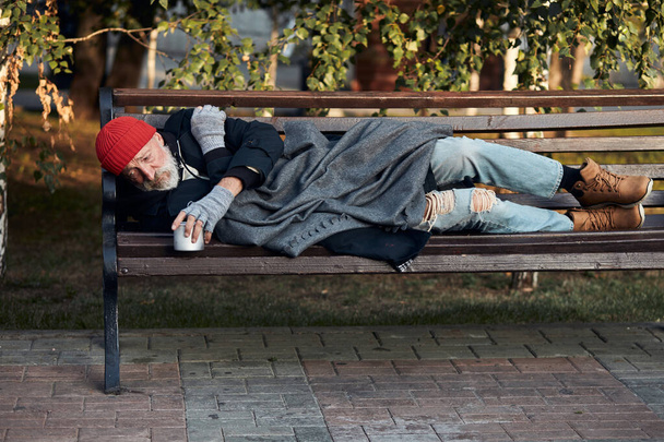 Poor homeless man lying on bench in cold weather - Zdjęcie, obraz