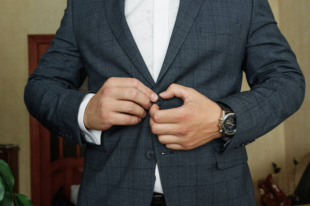 Hände eines Geschäftsmannes, Großaufnahme, Knöpfe an einer Jacke. Konzept des Geschäftsstils. - Foto, Bild