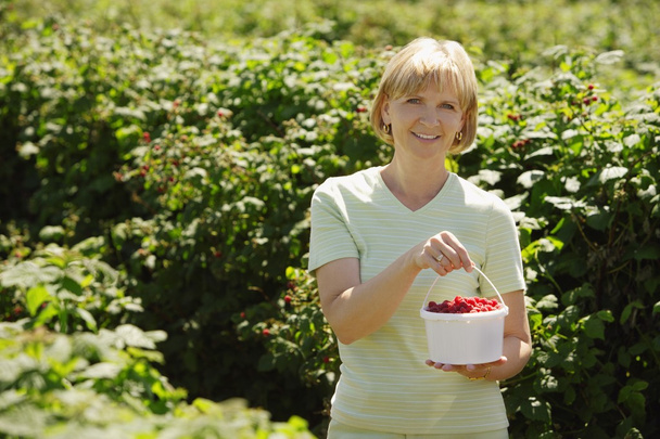 Woman Holding A Container Of Raspberries - Foto, afbeelding