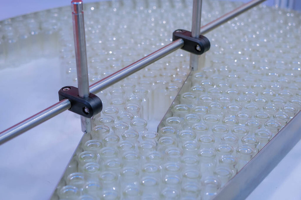 Concepto de tecnología farmacéutica automatizada: cinta transportadora con botellas de vidrio vacías
 - Foto, imagen