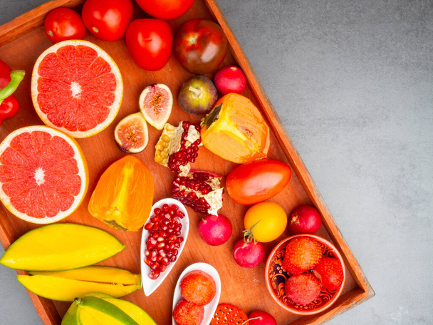 fresh red, orange, yellow fruit and vegetables rich in antioxidants, fiber, alfa carotene, lycopene, beta carotene, carotenoid, lutein, phosphorus, calcium, vitamin c. - Foto, afbeelding