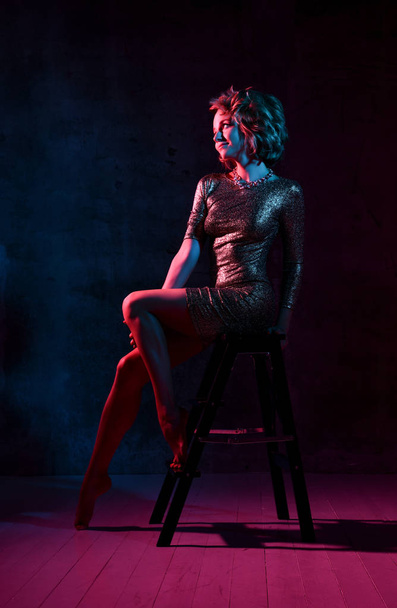 Attractive young girl in a tight shiny dress in the studio with color filters. - Fotografie, Obrázek