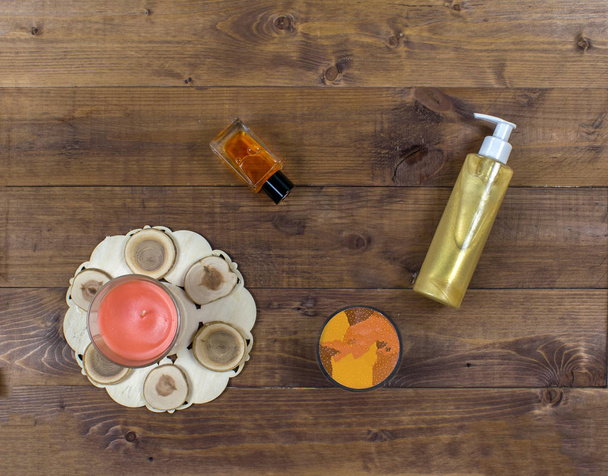 Plancha cosmética de otoño con productos de belleza, botella, exfoliante y vela de spa sobre un fondo de madera marrón
.  - Foto, imagen